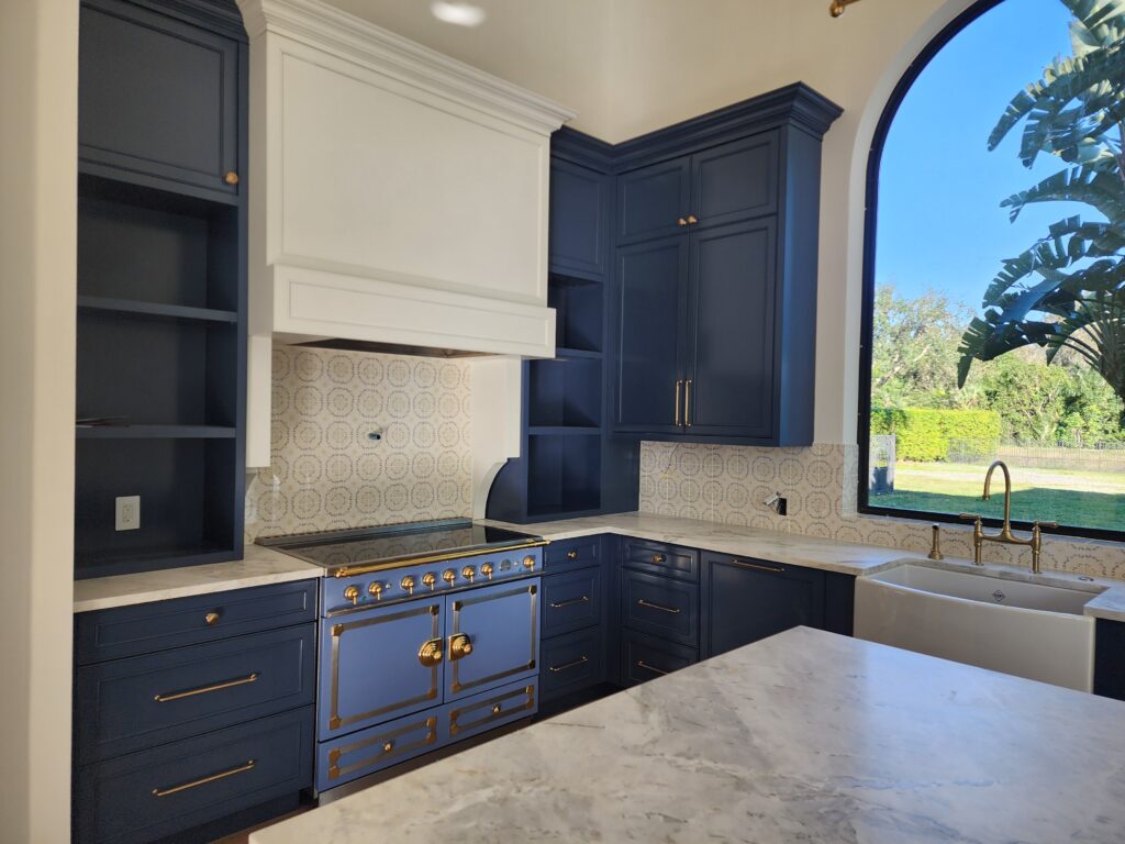 Premium blue range installed in a navy kitchen with custom cabinetry and arched window